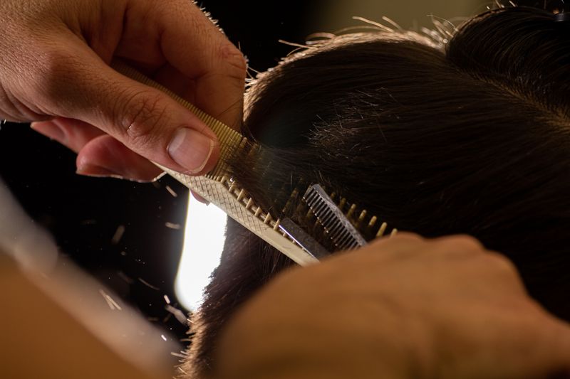 Close up of a stylist cutting hair with scissors and comb